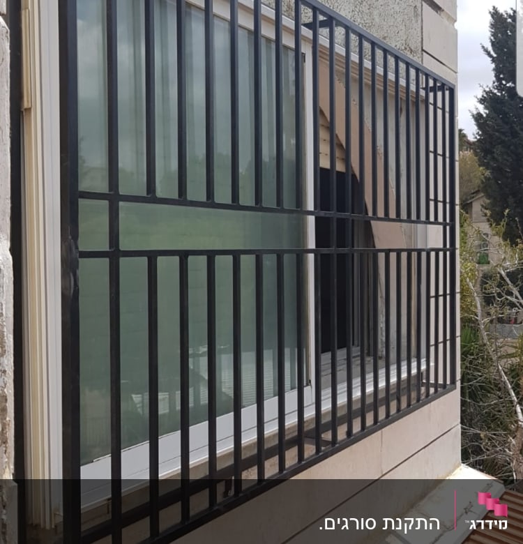 סורגי מתכת שחורים על חלון זכוכית